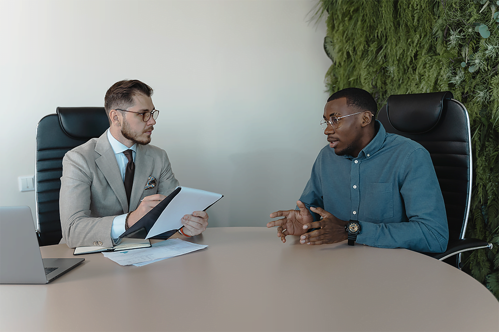 Employer interviewing candidate, sitting in conference room, employer holding application in hand